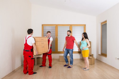 Removal team handling furniture and boxes in a North London home